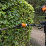 Homme qui taille une haie avec un taille haie sur perche de la marque Stihl